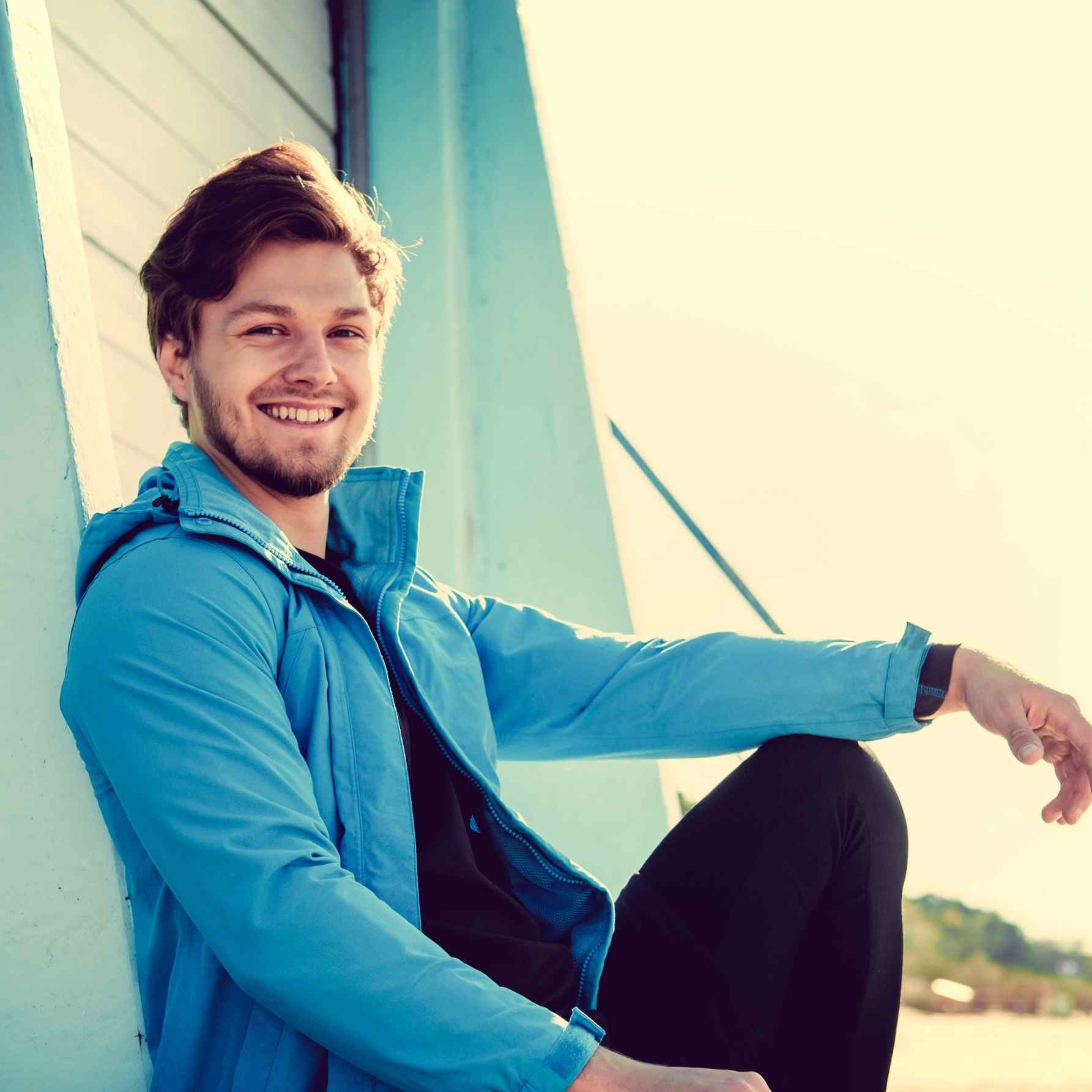 Smiling Man in Blue Jacket on Beach